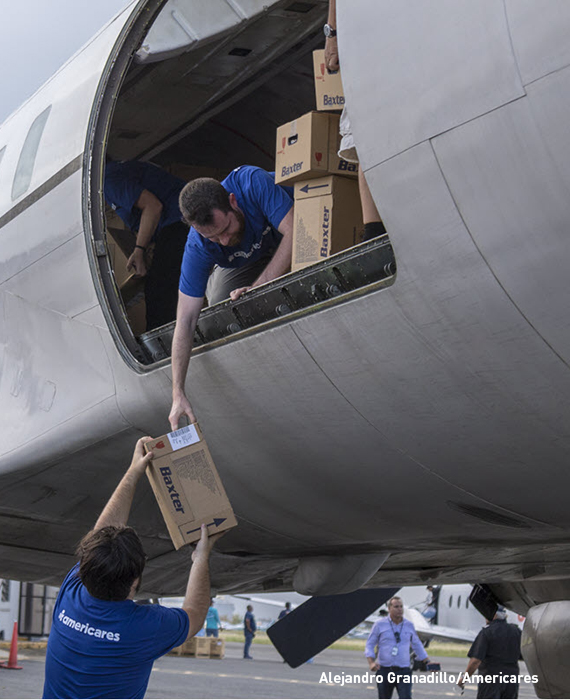 Volunteers unload boxes of supplies from a cargo jet